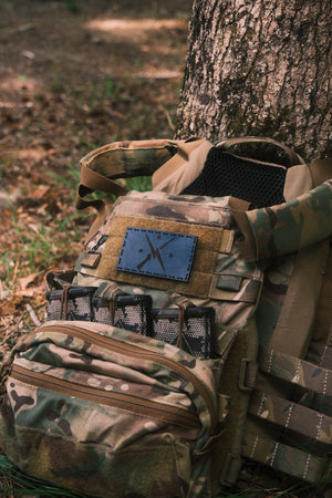 a carrier next to a tree with a blue leather patch with black thread that has the Minuteman design