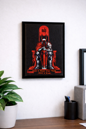 Framed canvas art with a red and black design of a figure on a throne in a room with a plant and desk.