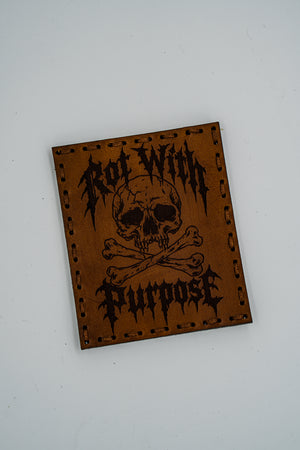 Rot with Purpose leather morale patch: skull and crossbones with Rot With Purpose in metal-style lettering, walnut leather, hand sewn with brown thread and hook backing