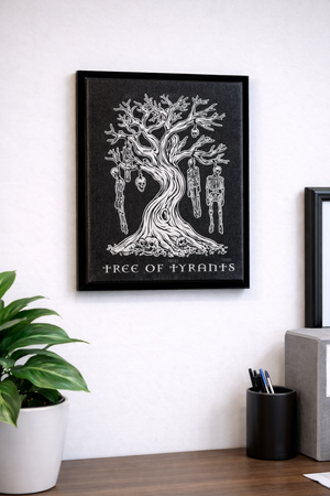 Framed artwork titled 'Tree of Tyrants' on a white wall with a plant and container in the foreground.